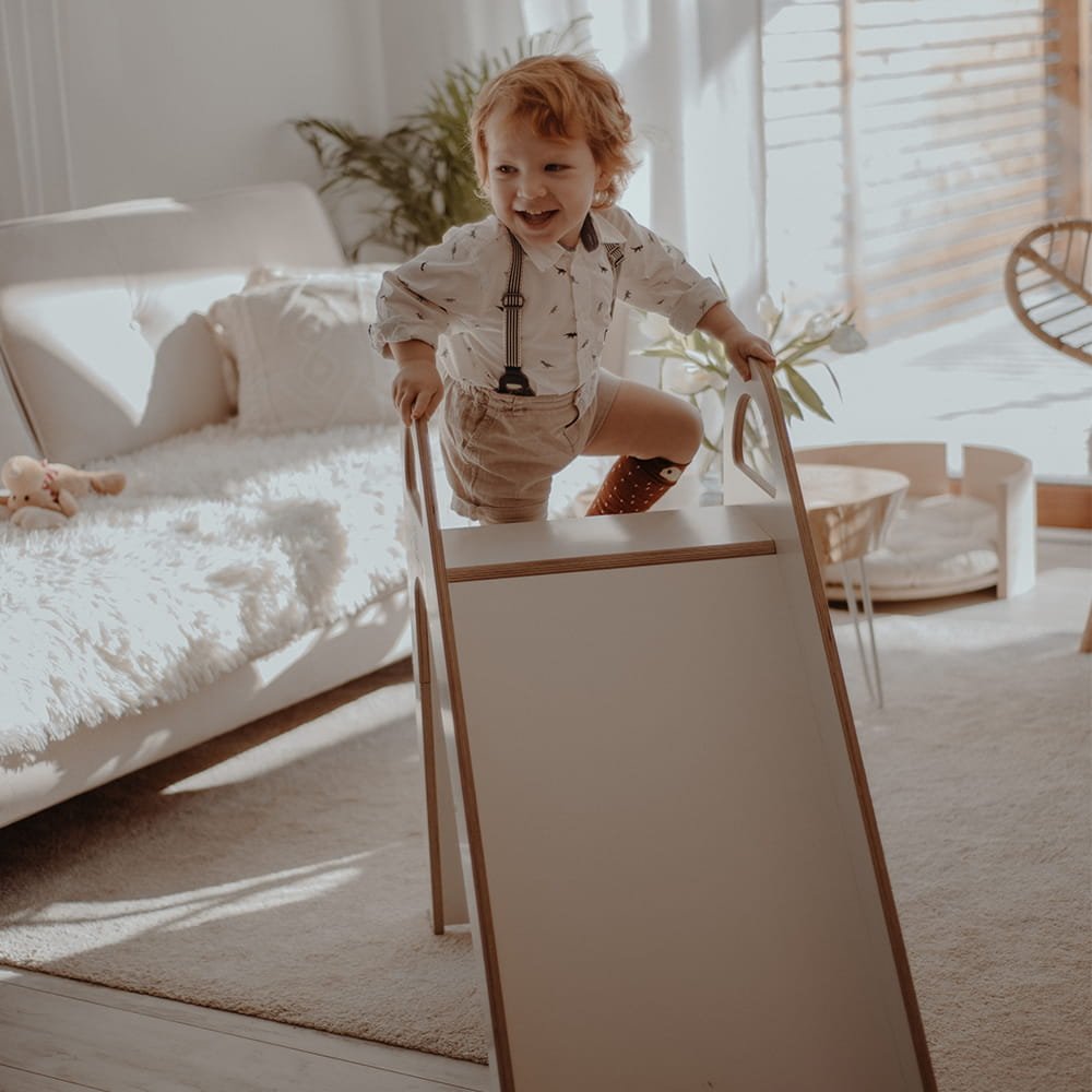 1. Child climbing a white wooden slide in a sunlit living room