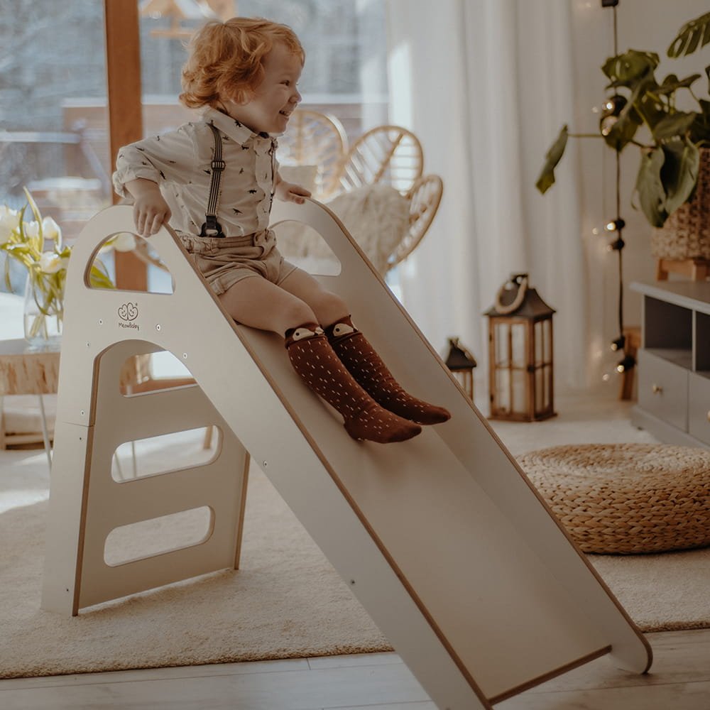 1. Child sliding down a white wooden slide in a cozy living room