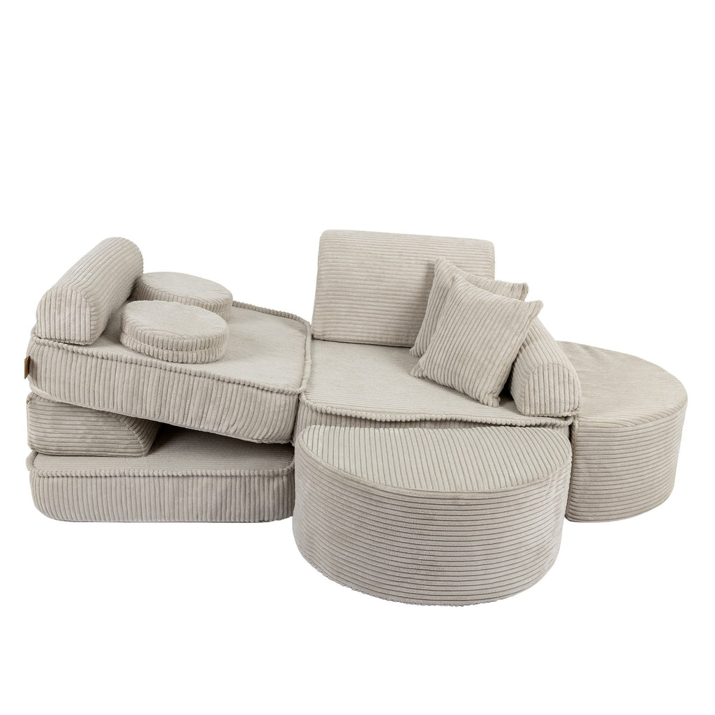 5. Modular children's sofa in ecru with ribbed texture, arranged in a layered layout with cushions, shown in a studio setting.