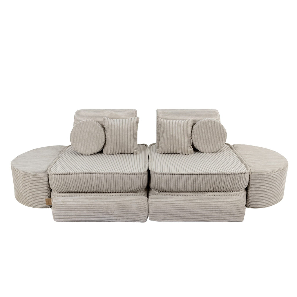 2. Ecru modular sofa for kids with ribbed texture, arranged in a symmetrical layout with circular and square cushions, shown in a studio setting.