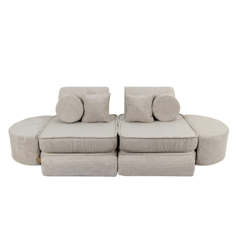 2. Ecru modular sofa for kids with ribbed texture, arranged in a symmetrical layout with circular and square cushions, shown in a studio setting.