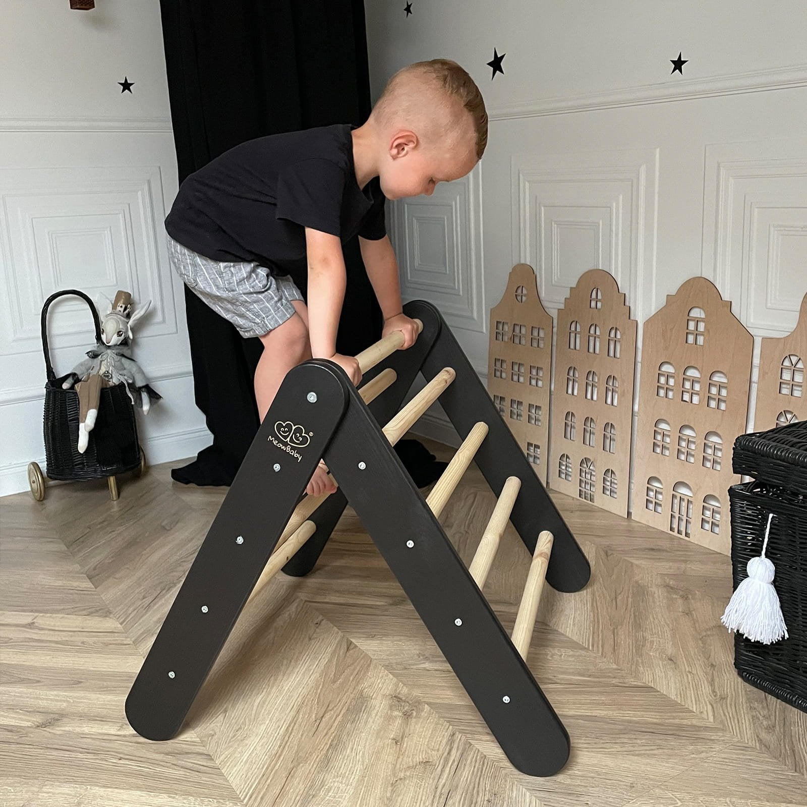 4. Child climbing black and natural wood ladder in playroom setting with decorative elements