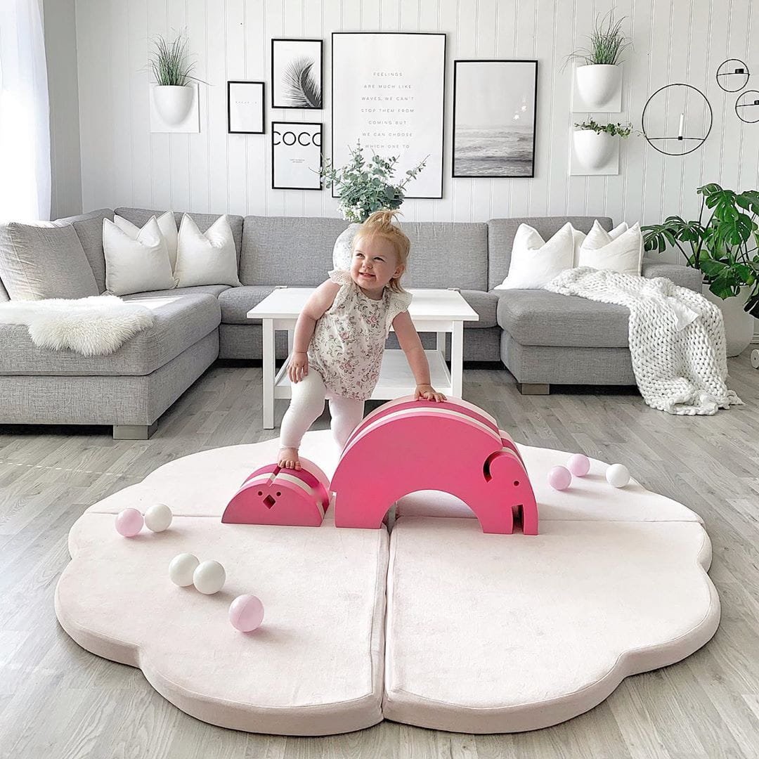 7. Child playing on a pink cloud-shaped velvet play mat with toys in a stylish living room