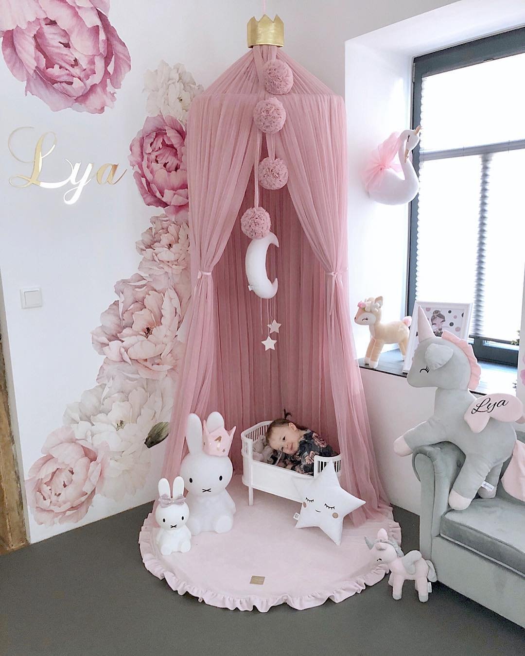 1. Baby sleeping on pink round play mat with frill under pink canopy in nursery