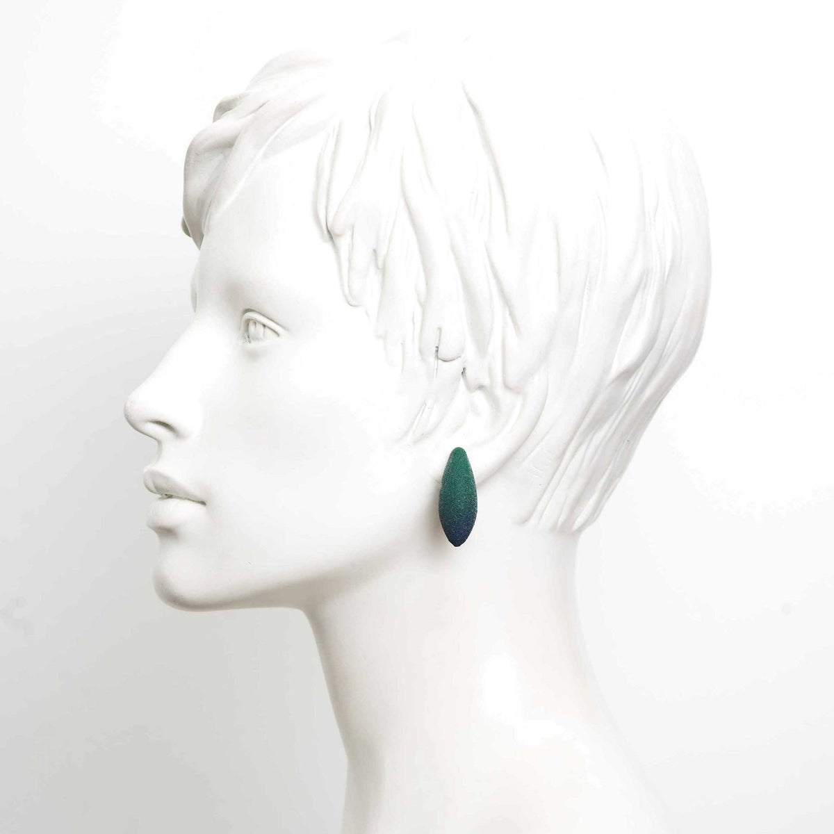 1. Mannequin wearing a single green Mini Avocados earring by Tanel Veenre, showcasing its elegant drop shape