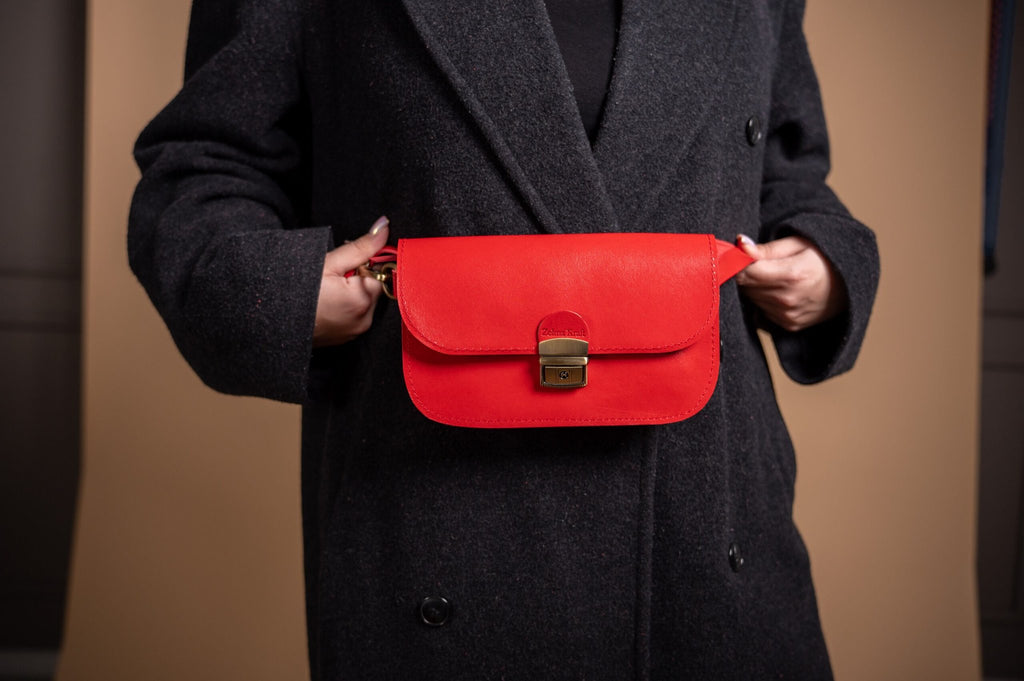 4. Close-up of Zelma Kraft red leather saddle bag worn crossbody, highlighting buckle closure