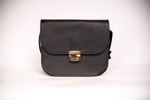 5. Studio shot of Zelma Kraft black leather saddle bag with buckle closure, shown from front