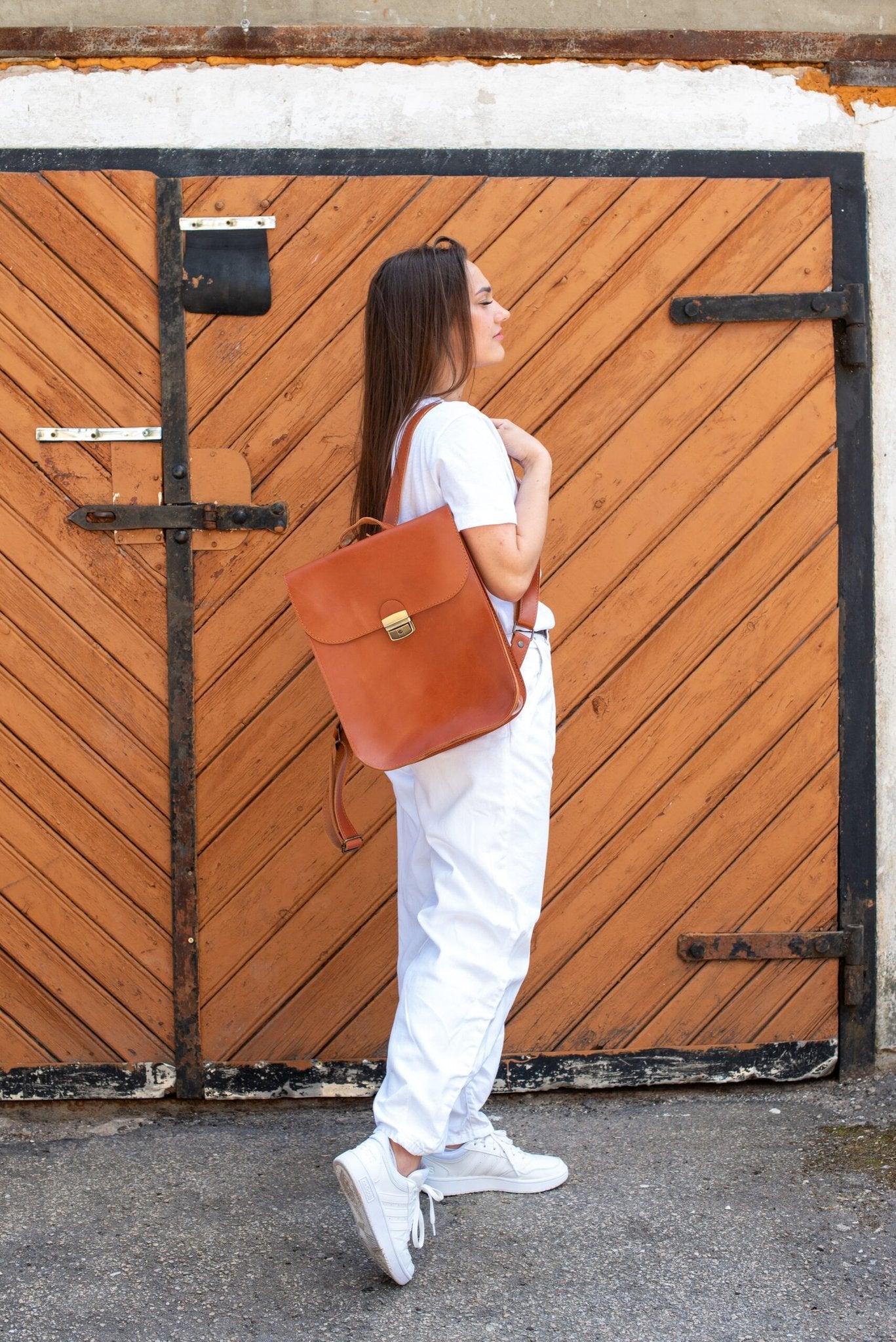 6. Woman wearing Zelma Kraft light brown leather backpack, side view in lifestyle setting