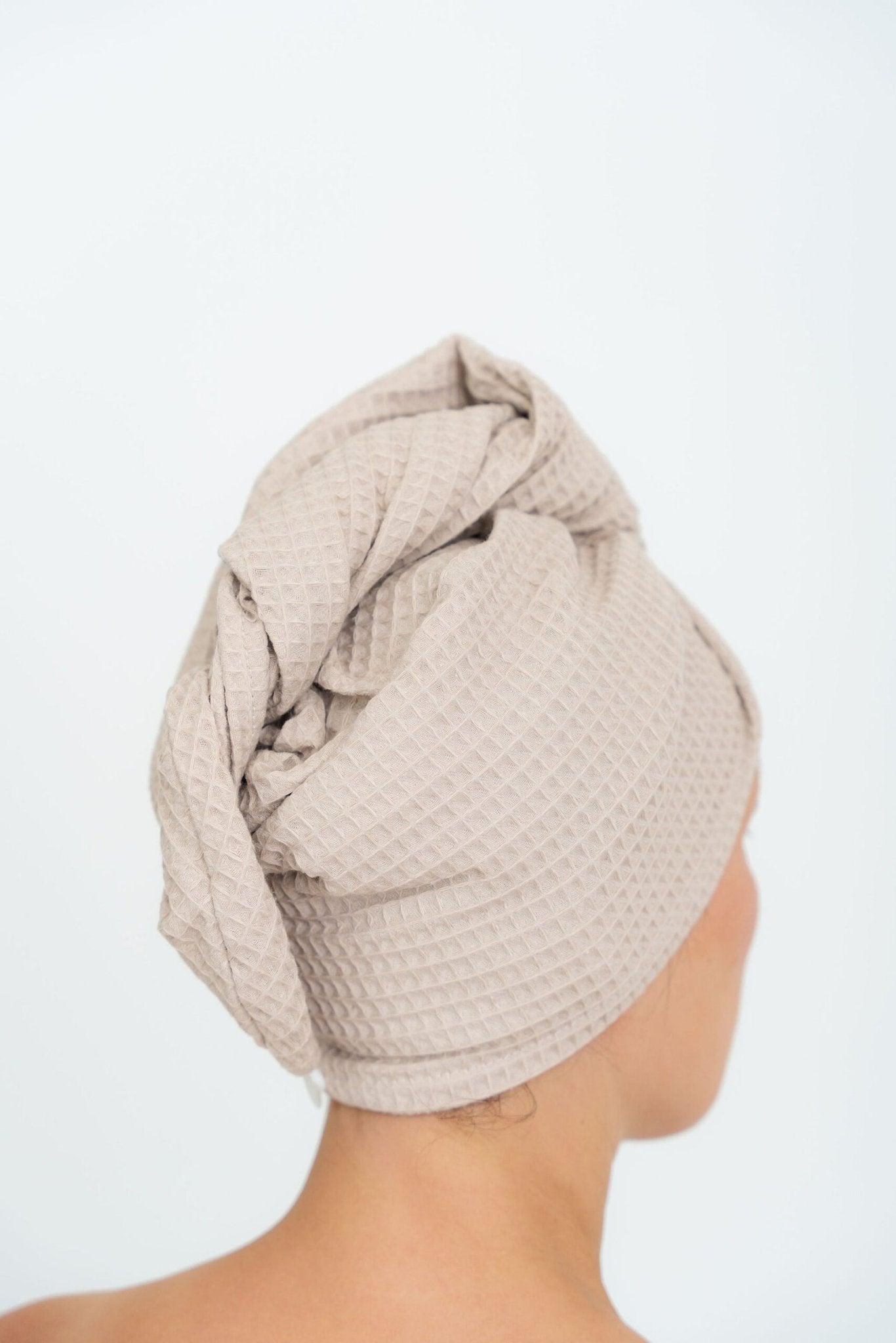 2. Back view of woman wearing beige cotton hair towel with button closure, highlighting texture