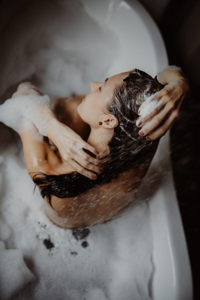 1. Woman using V.O.H solid shampoo in a bubble bath, showcasing eco-friendly hair care routine
