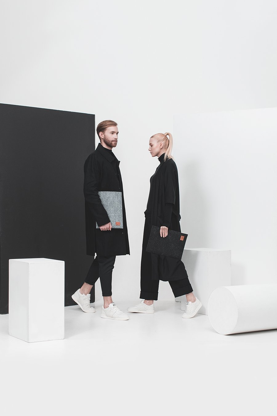 1. Unisex models holding Nordhale Bodem grey laptop sleeve in minimalist studio setting