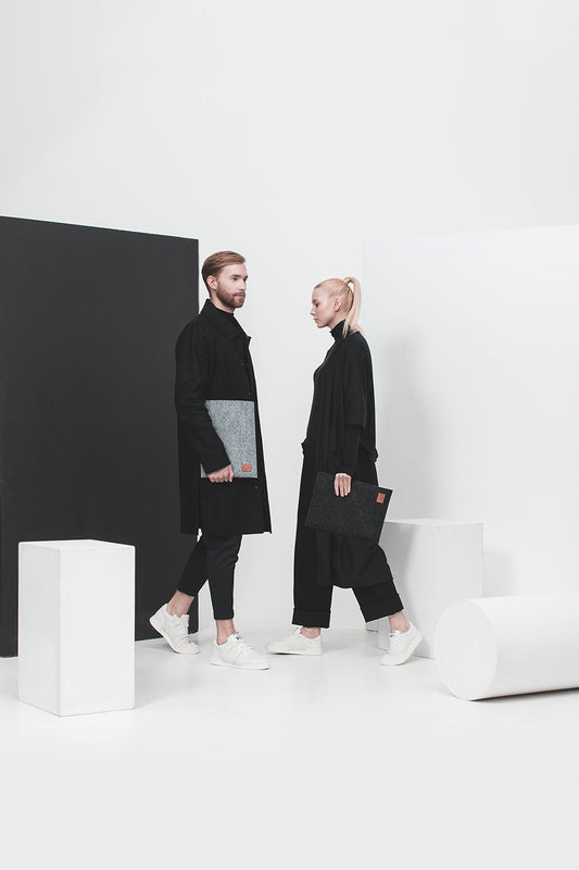 1. Unisex models holding Nordhale Bodem grey laptop sleeve in minimalist studio setting
