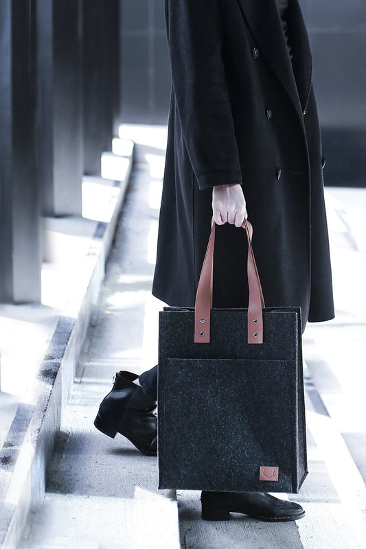1. Unisex black Nordhale Hennes Tote Bag with leather handles, styled by male and female models in a minimalist studio setting