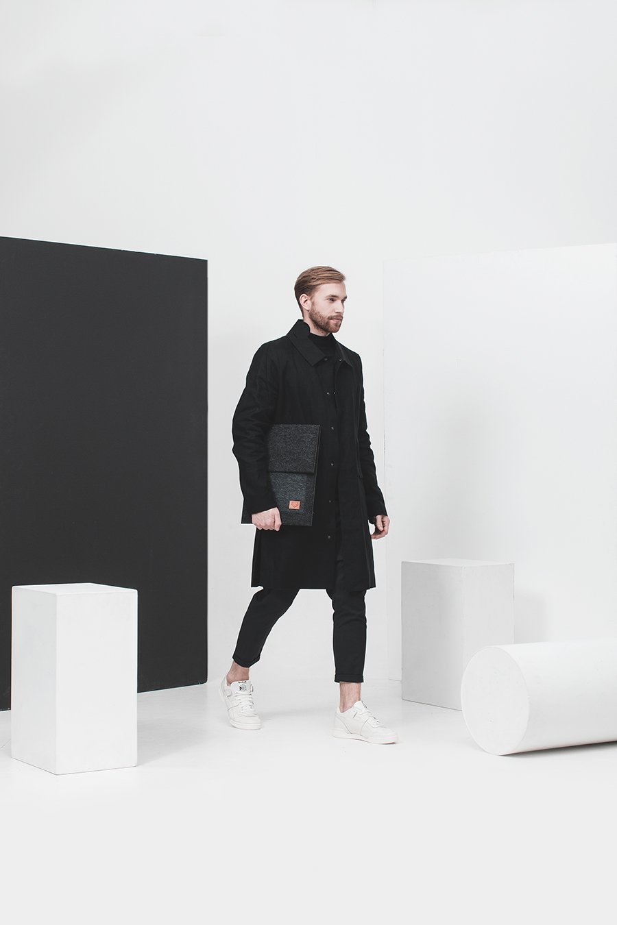 1. Man holding Nordhale Malmö black laptop sleeve in minimalist studio setting