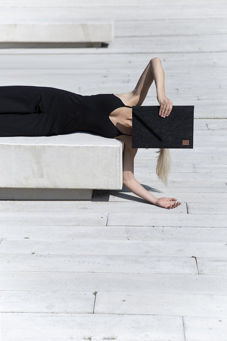 2. Woman holding Nordhale Skive black clutch and laptop case while reclining outdoors