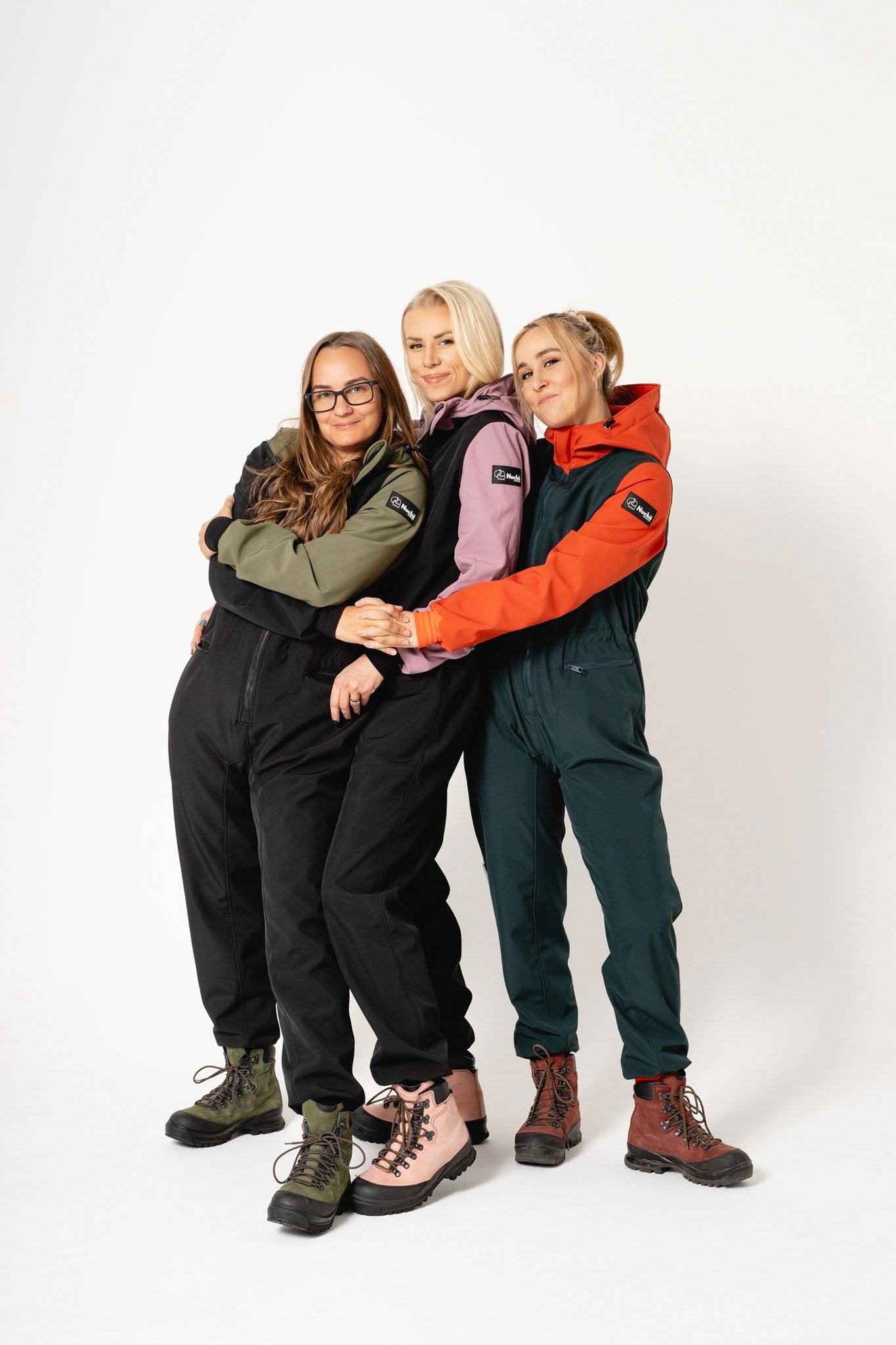1. Women's CAROLA softshell overall by Nuckö in black and green, worn by three models in studio setting