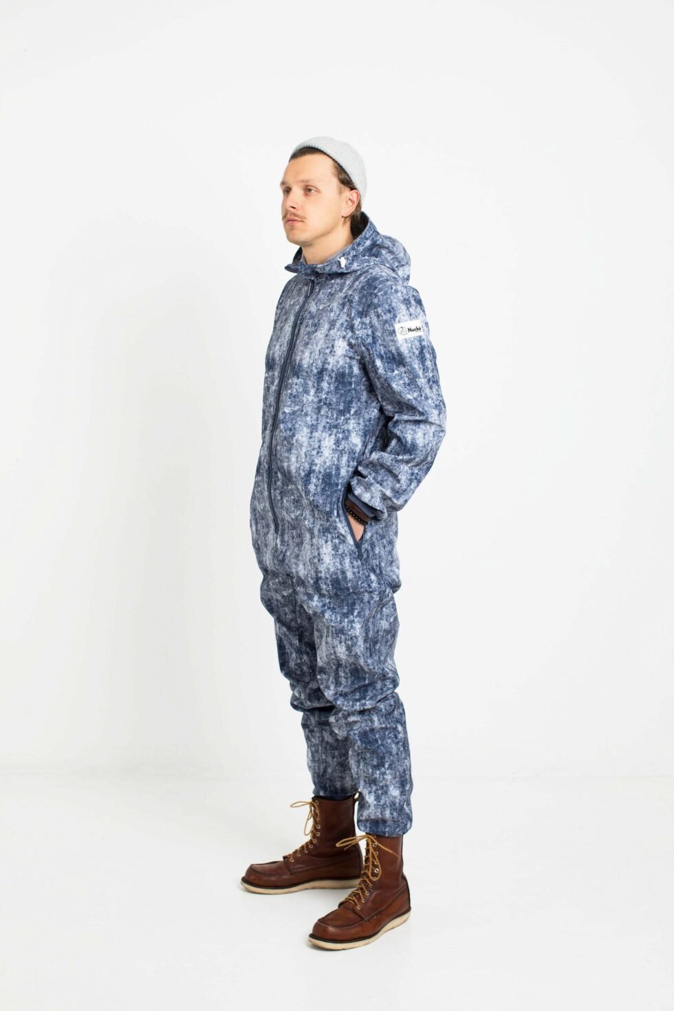 4. Man in Nuckö ERGO softshell overall with blue digital print, standing in studio, side view with hands in pockets