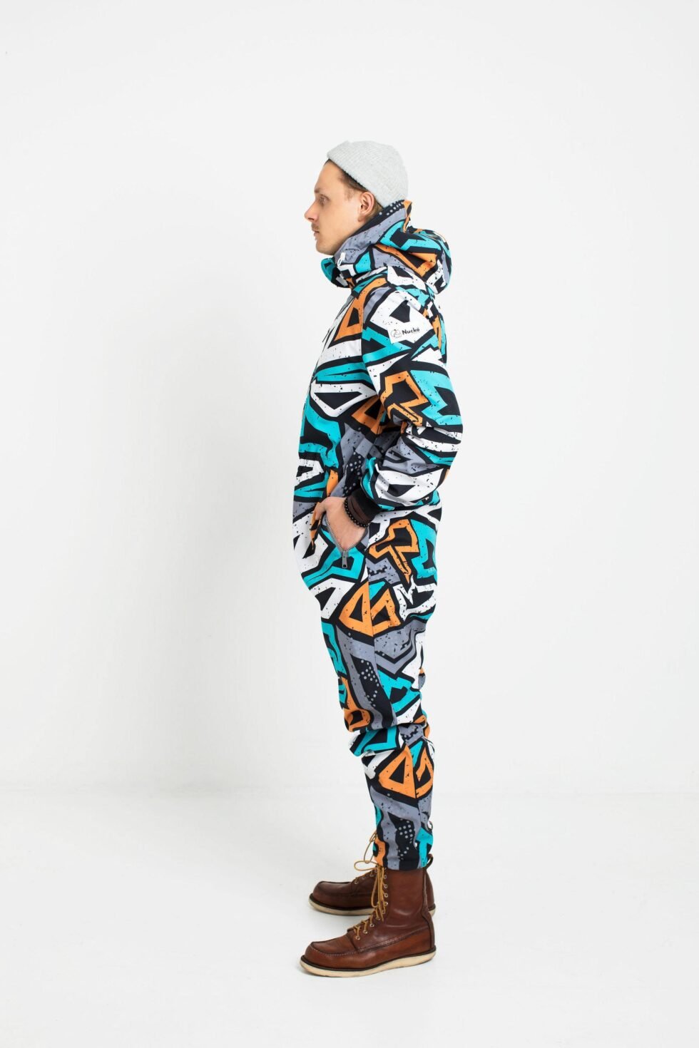 2. Side view of man in Nuckö TANIEL softshell overall with adjustable hood and waist, geometric pattern, studio background