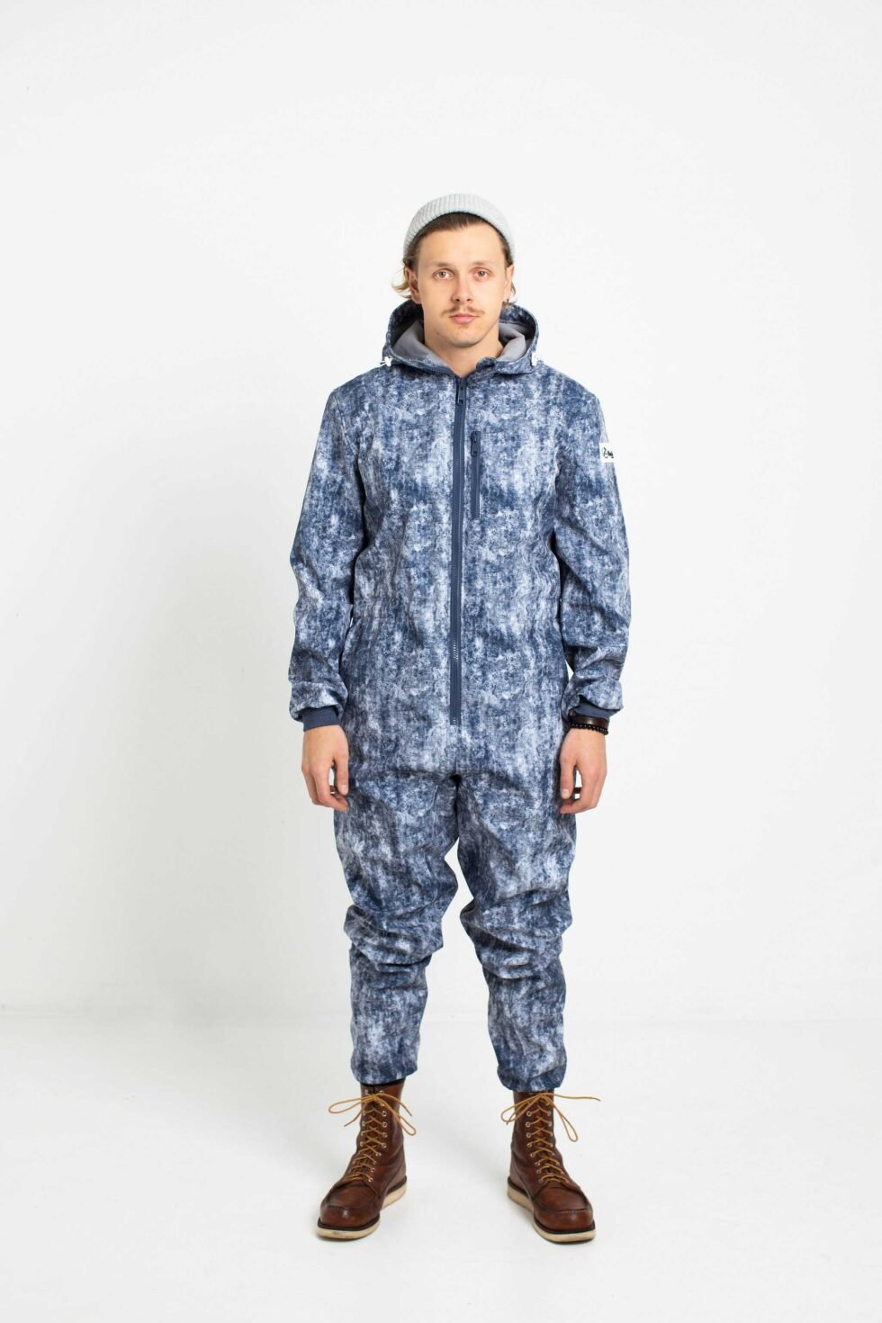 1. Man wearing Nuckö ERGO softshell overall with blue digital print, standing in studio with hands by sides