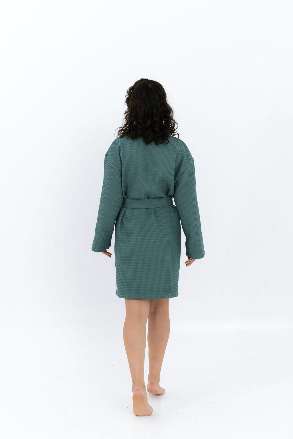 7. Woman walking away in green waffle robe with belt, shown from back in studio