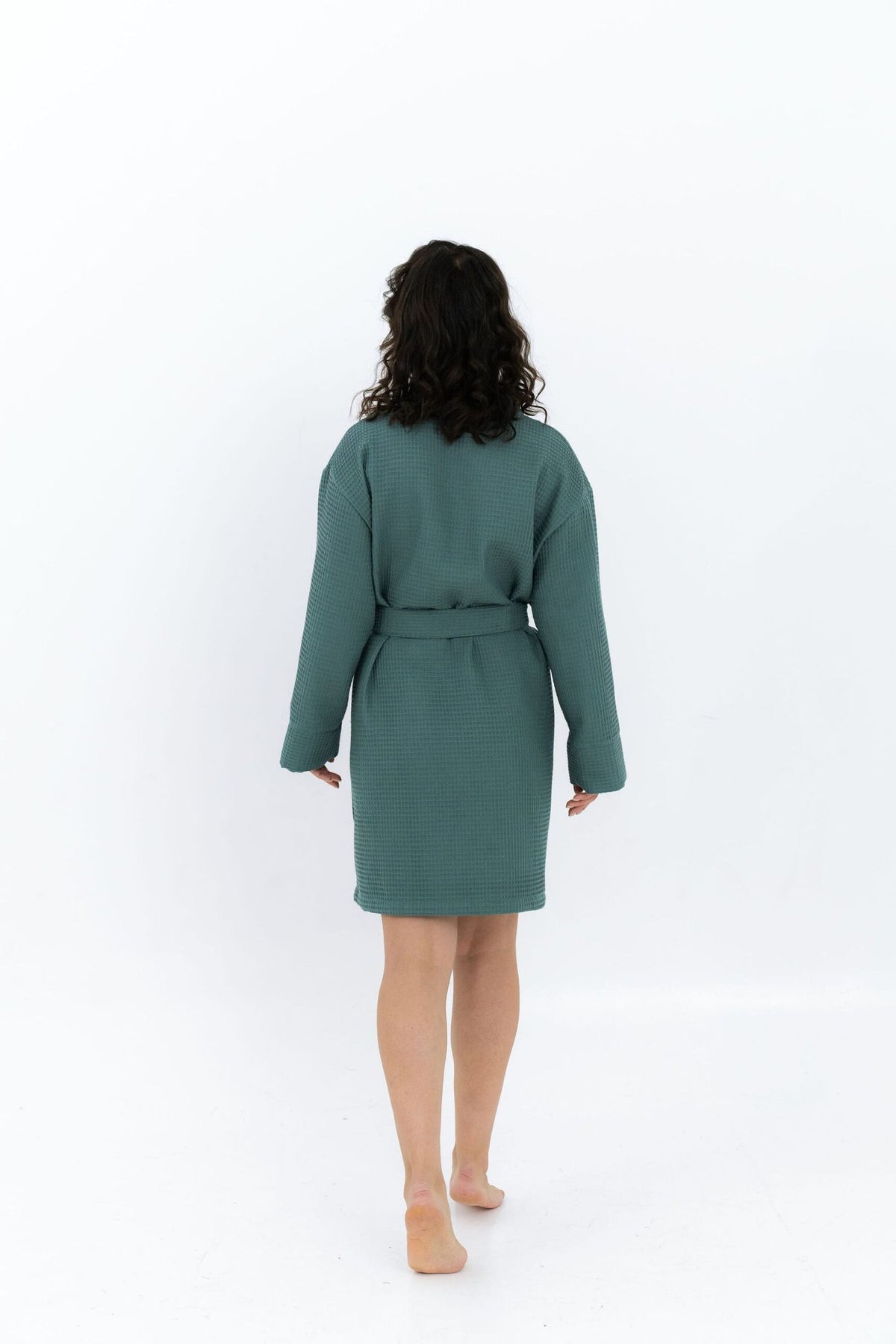 7. Woman walking away in green waffle robe with belt, shown from back in studio