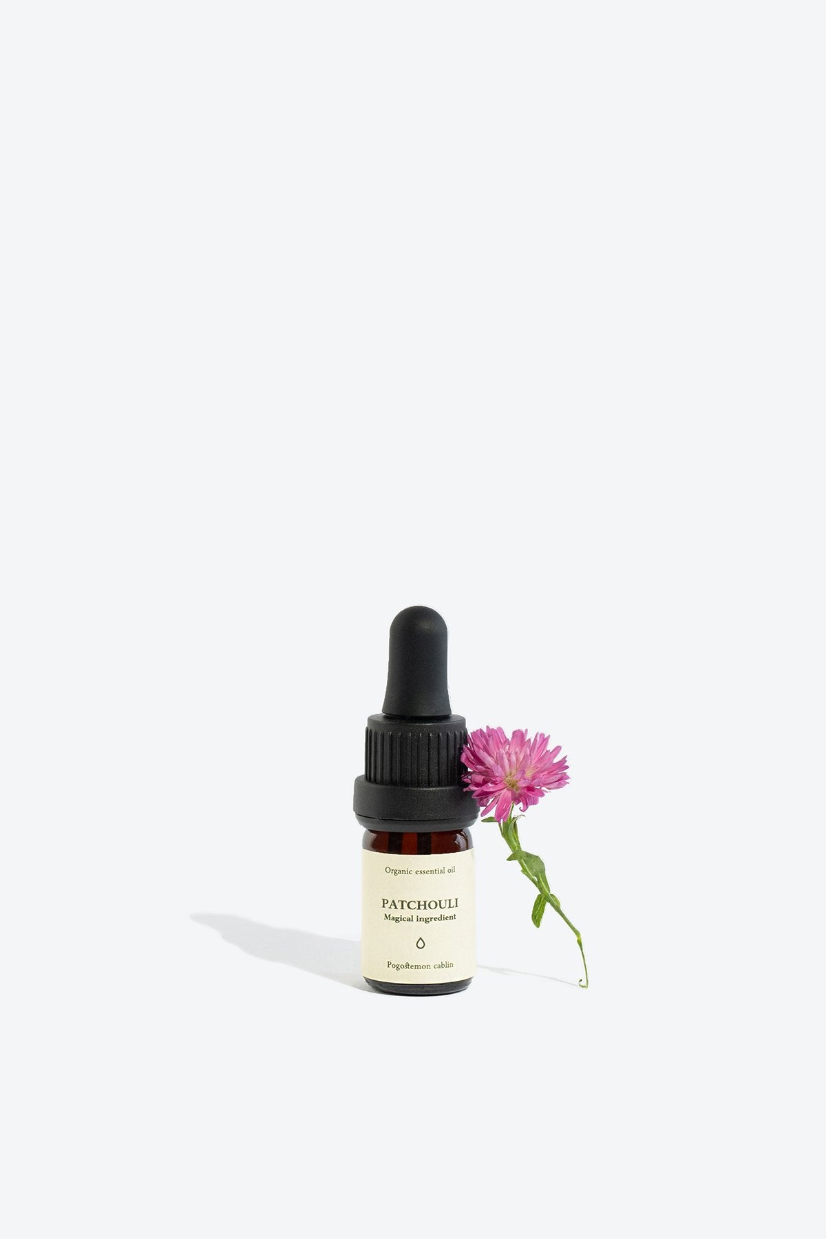 2. Smells Like Spells PATCHOULI Essential Oil with pink flower, 5 ml glass bottle, studio setting