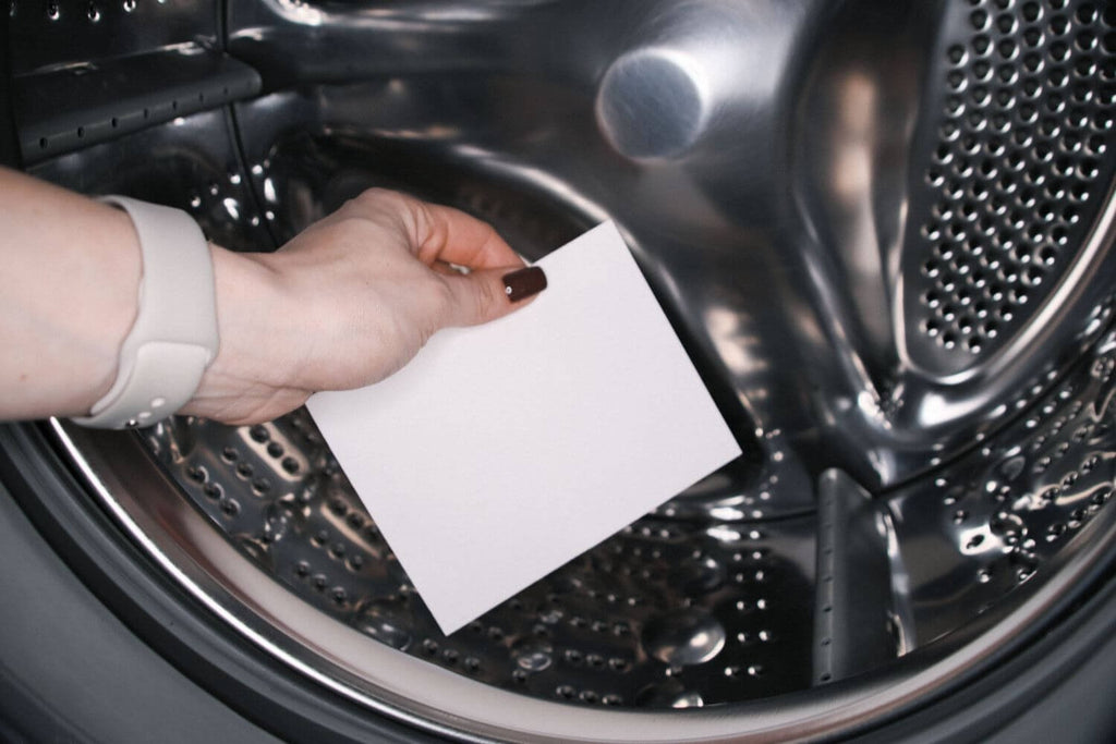 1. Person placing GoGoNano laundry detergent sheet into washing machine drum, demonstrating ease of use