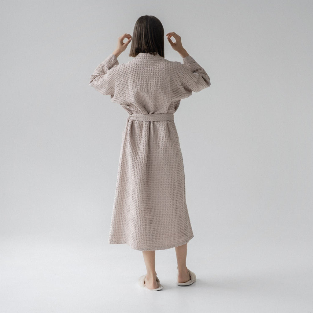 2. Woman shown from back wearing powder-colored honeycomb waffle bathrobe with waist tie, standing in a studio