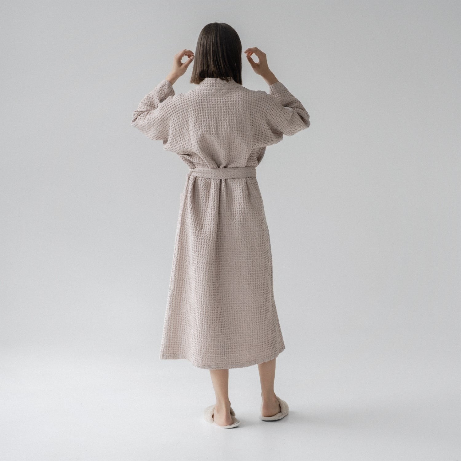 2. Woman shown from back wearing powder-colored honeycomb waffle bathrobe with waist tie, standing in a studio