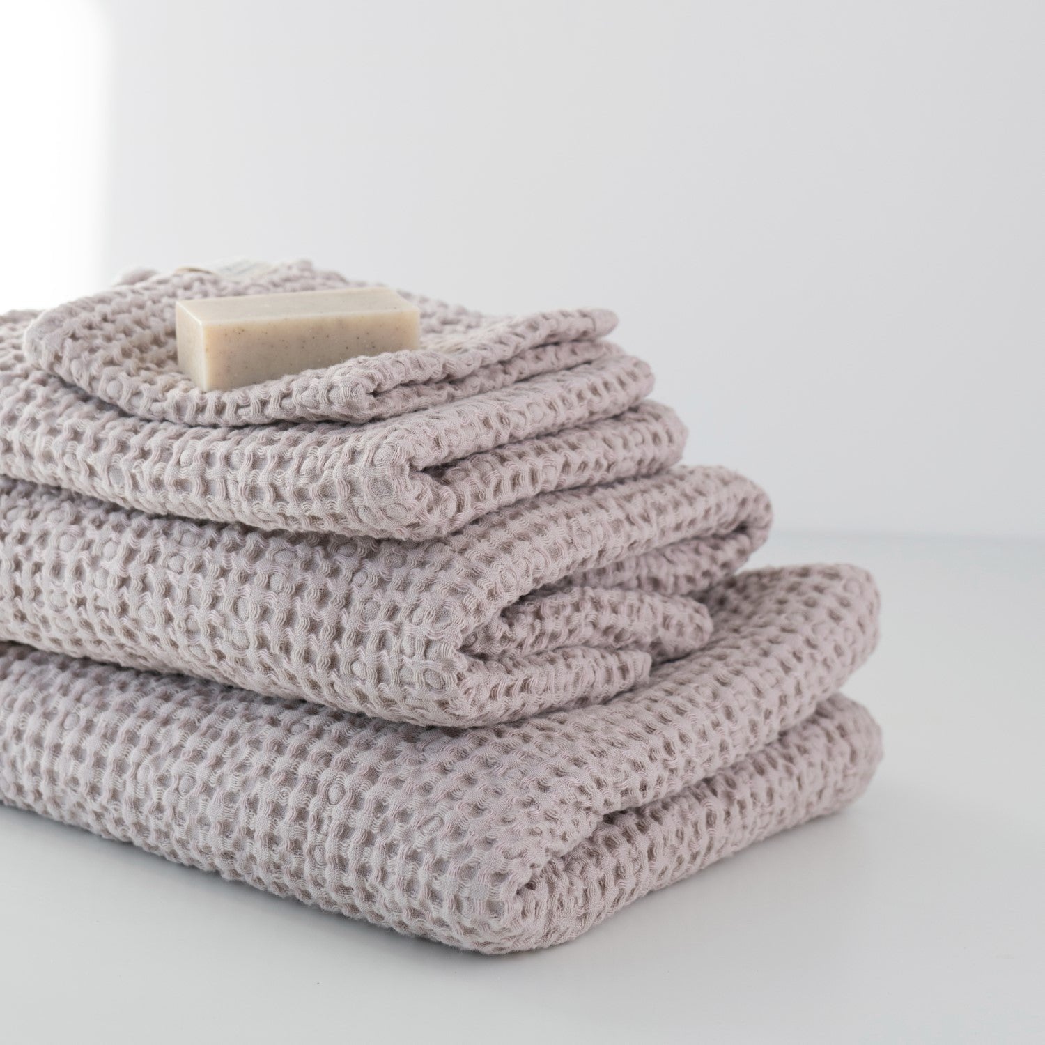 2. Close-up of folded powder-colored honeycomb waffle towels with a soap bar, highlighting texture