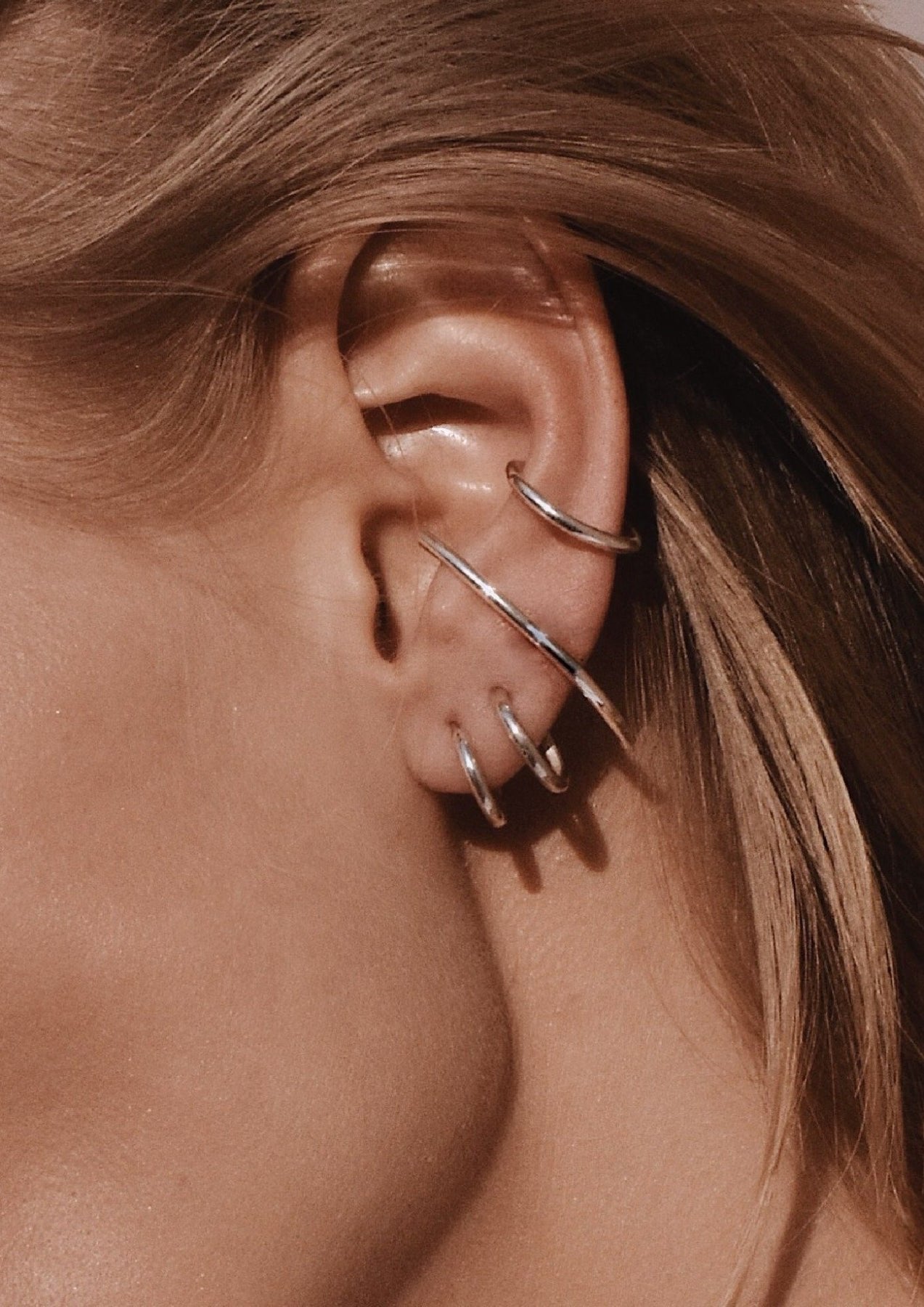 4. Close-up of multiple silver earrings including NO MORE Radius earrings, showing layered look