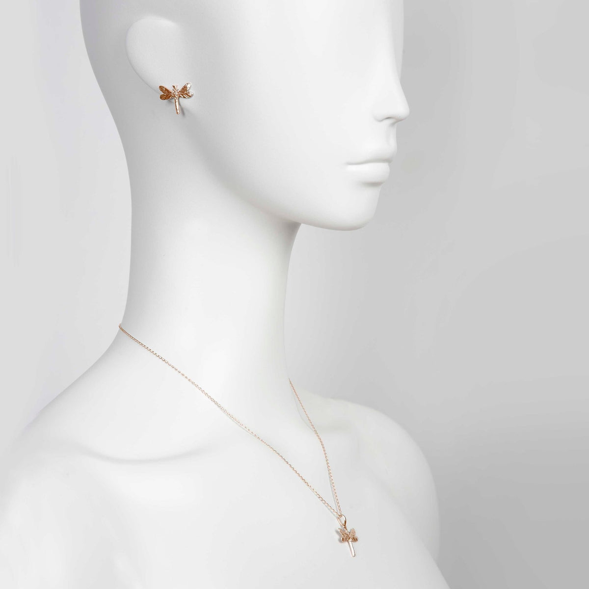 1. Mannequin wearing rose gold dragonfly pendant necklace and matching earring, side profile view