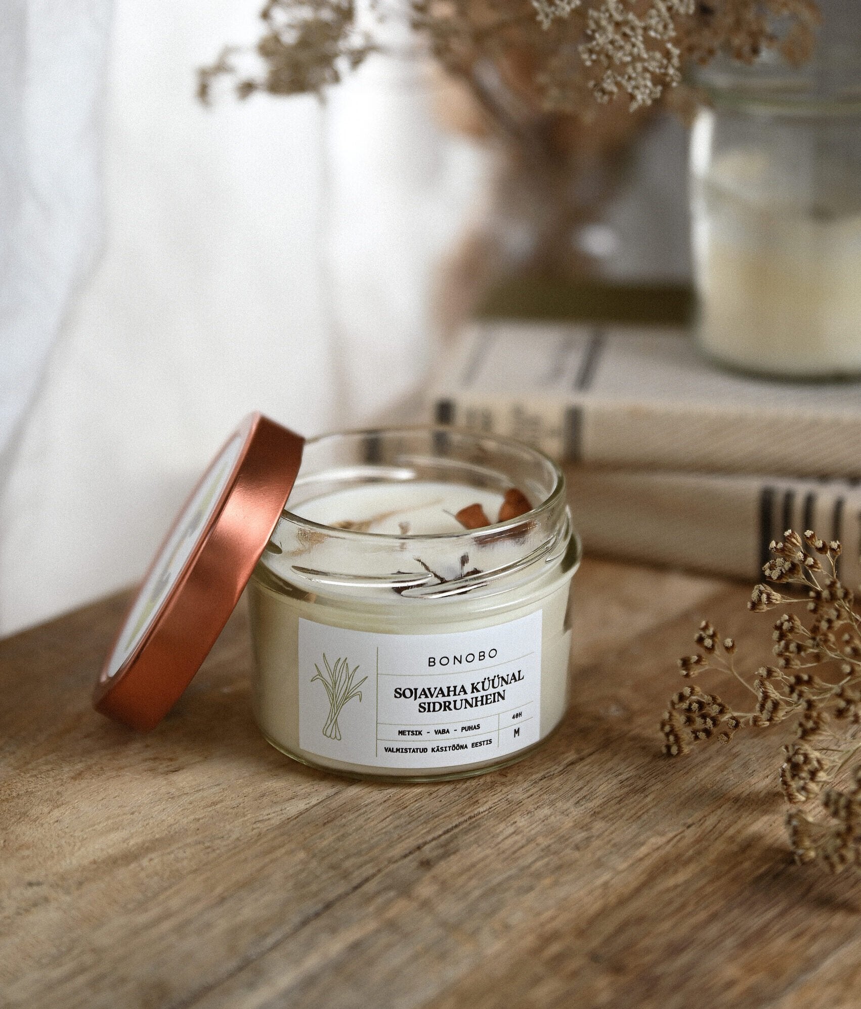 3. BONOBO Lemongrass scented candle with lid off, placed on a wooden surface with books