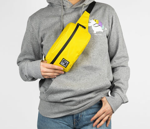 1. Person wearing yellow waist bag with black zipper across chest, dressed in grey hoodie with Moomin print