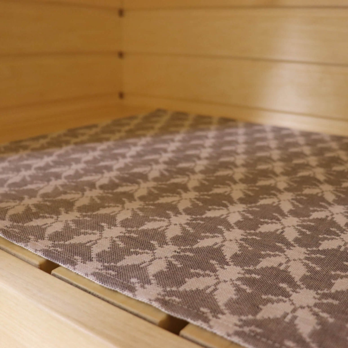 2. Close-up of sauna bench seating pad featuring Hiiumaa fly pattern in beige and brown, highlighting fabric texture, by LOKO