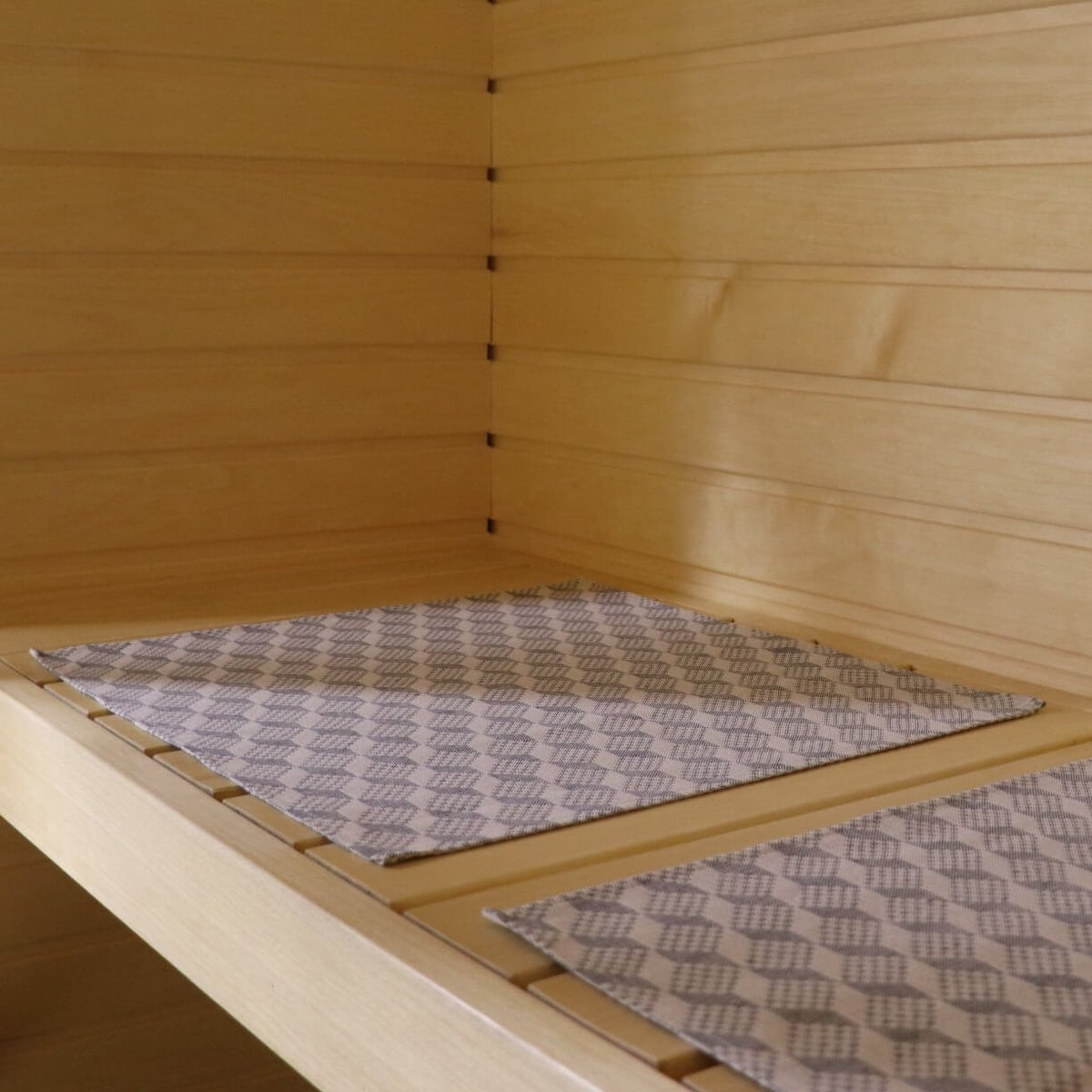 2. Two LOKO sauna bench seating pads with Viru County mitten pattern on wooden sauna bench