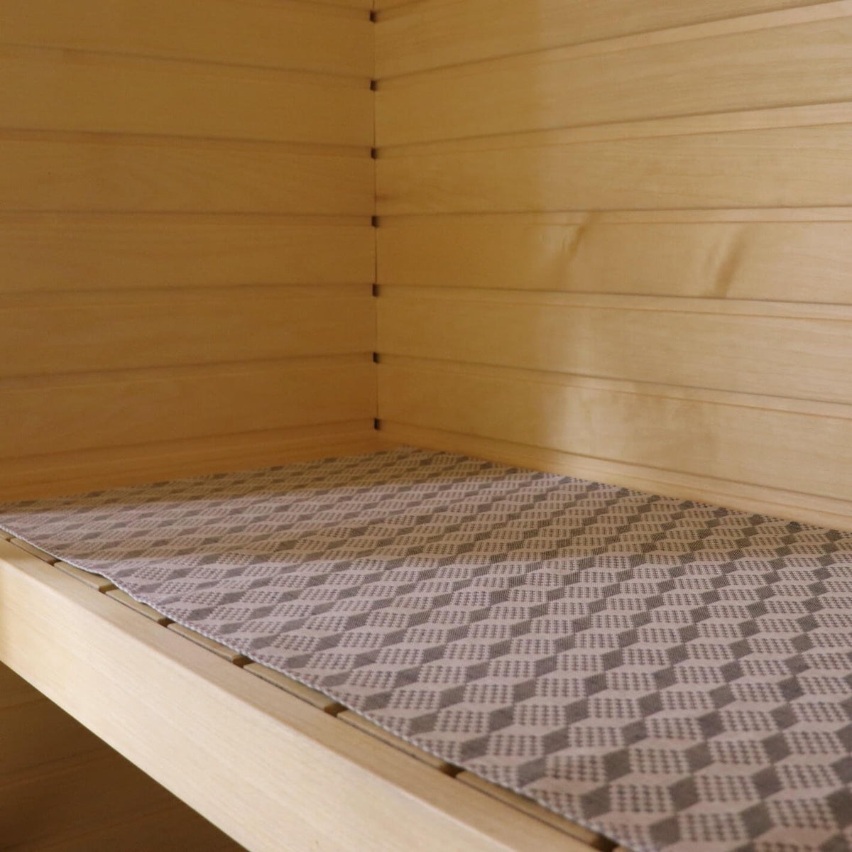 1. Sauna bench with LOKO seating pad featuring traditional Viru County mitten pattern in a light wood sauna setting