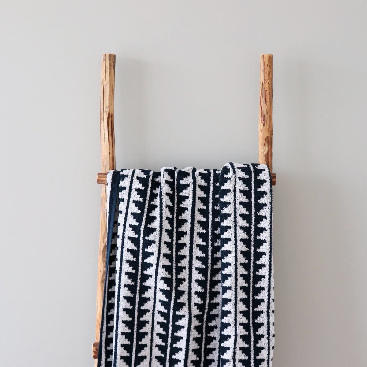 1. Black and white terry sauna towel with Saaremaa mitten pattern draped over wooden ladder against neutral wall