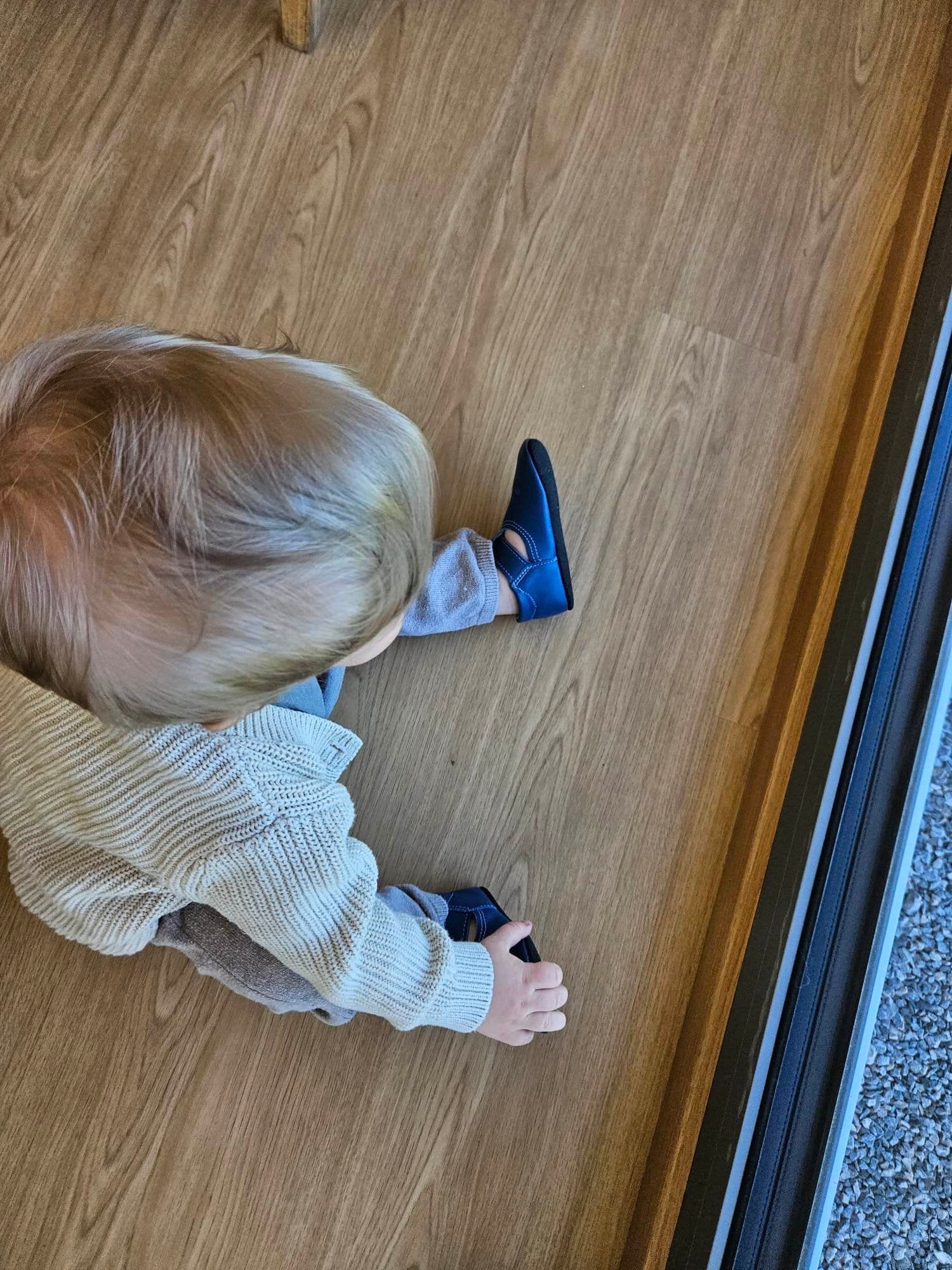 2. Child in Omaking Mutsu blue slippers, sitting on floor with view of slippers