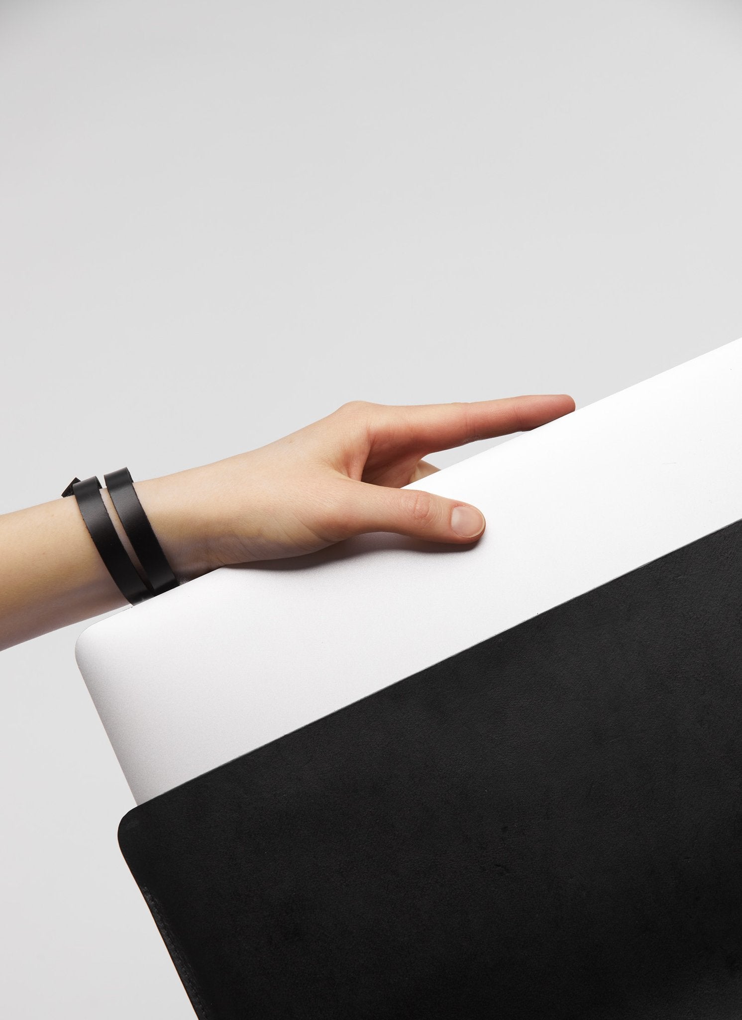 4. Hand holding black leather laptop sleeve with laptop partially visible