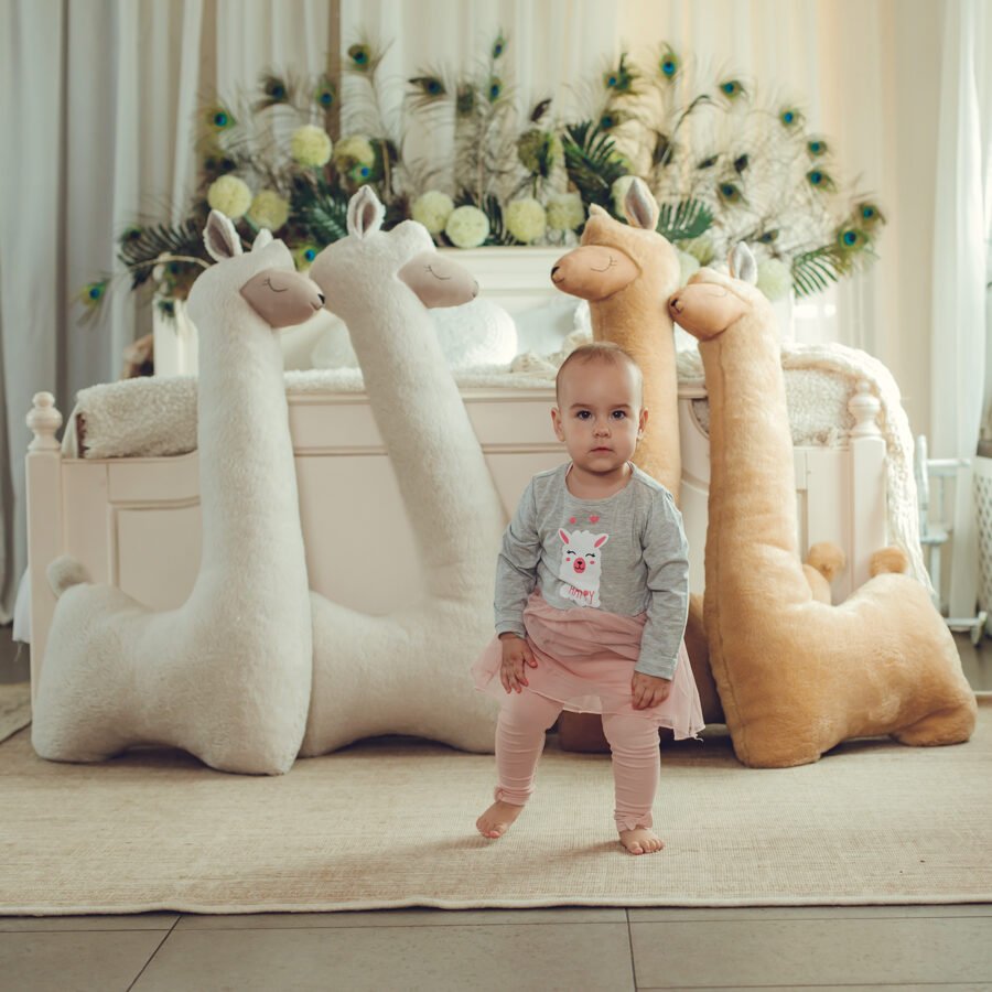 5. Child standing in front of rust and beige alpaca plush toys in stylish bedroom