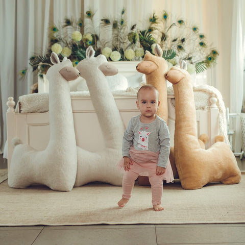 5. Child standing in front of rust and beige alpaca plush toys in stylish bedroom