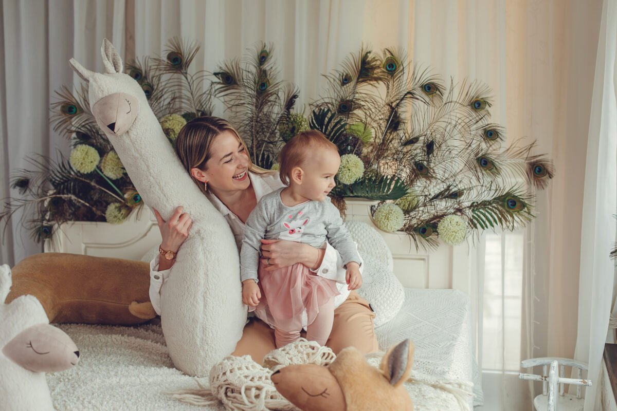 7. Child standing in front of beige and rust giant plush alpaca toys in decorated room