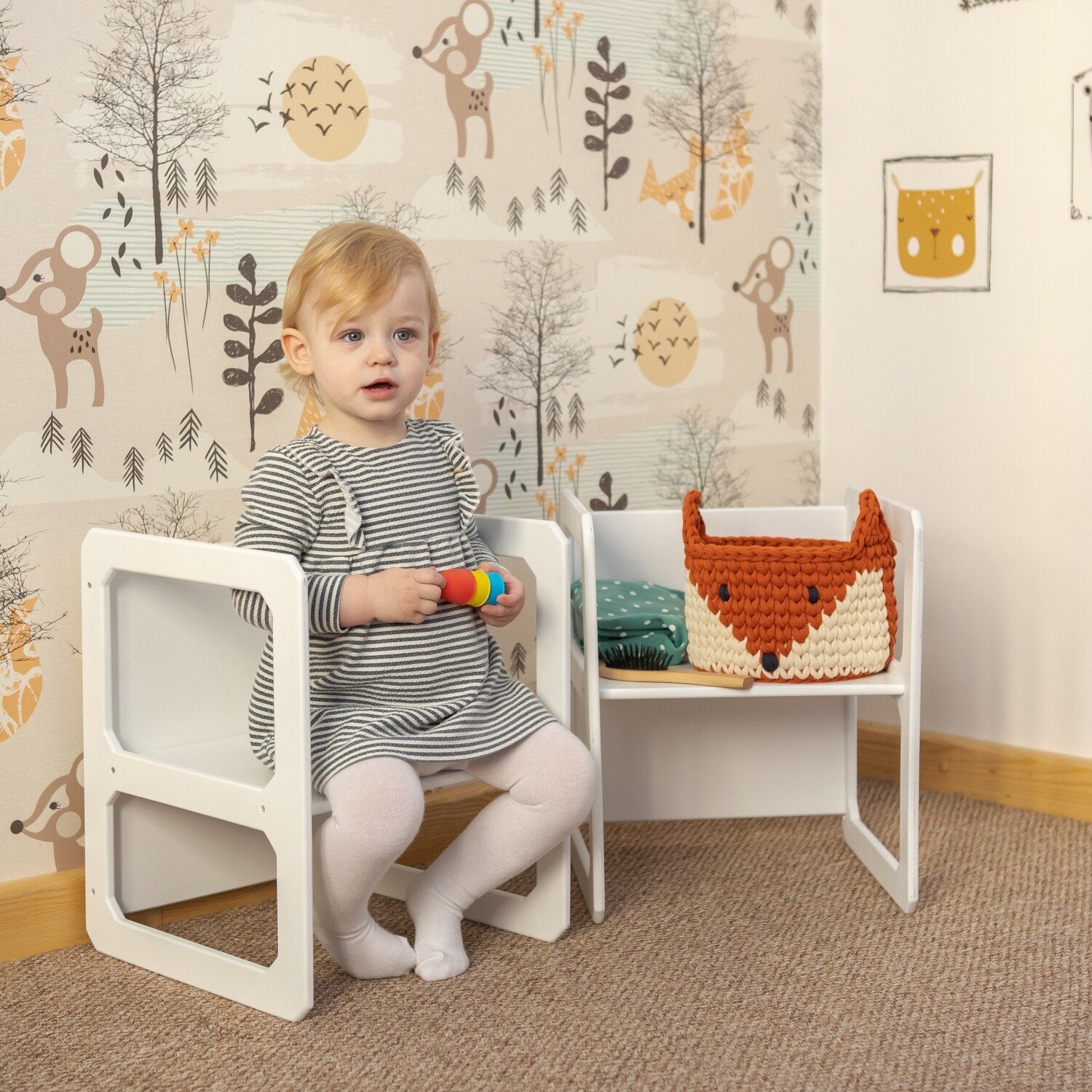 9. Toddler sitting on white Montessori chair with toys in nursery with animal wallpaper