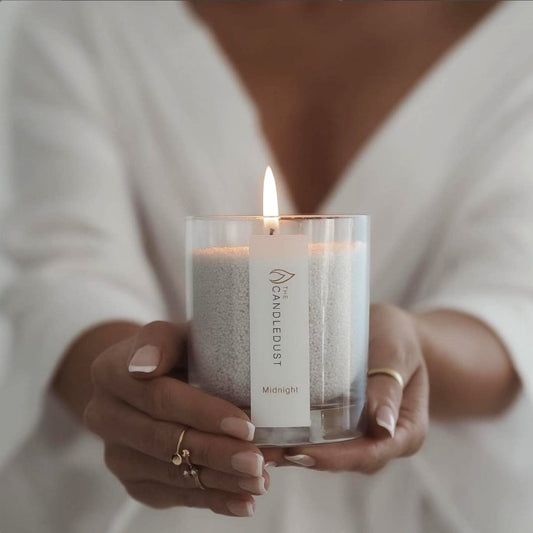 2. Woman holding a lit Candledust Powdered Candle in Glass - Midnight, showcasing elegant design