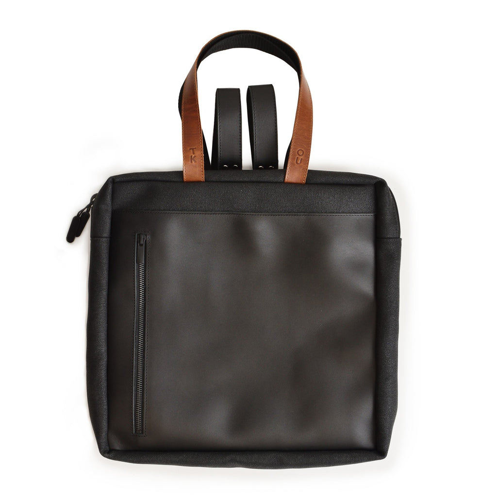 2. Studio image of the Omaking Stockholm Backpack in black, highlighting the front design with leather accents and secure zipper pocket