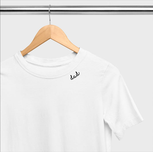 2. White organic cotton t-shirt with 'dad' embroidery on collar, displayed on a hanger in a studio setting