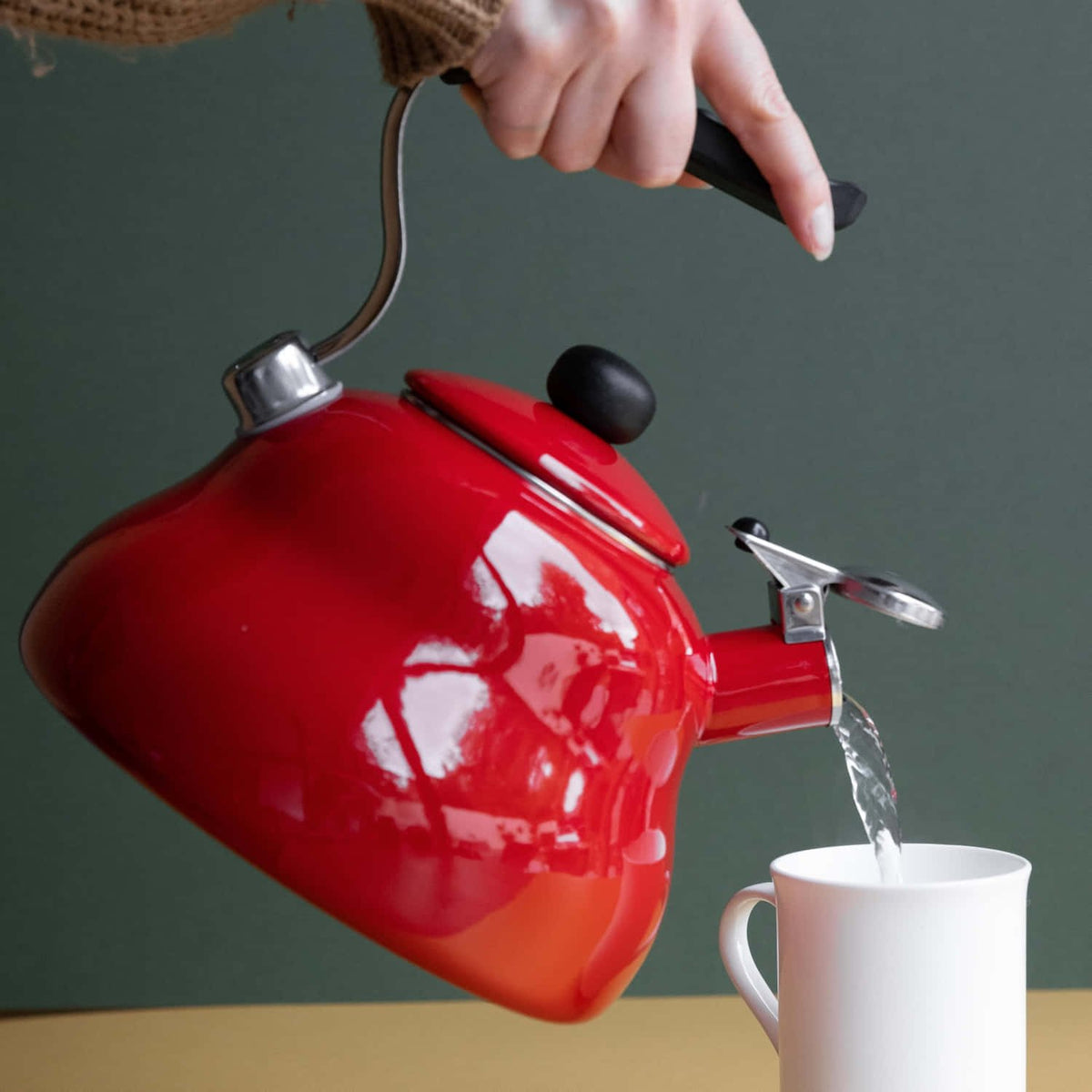6. Person pouring water from red La Cafetière kettle into white mug