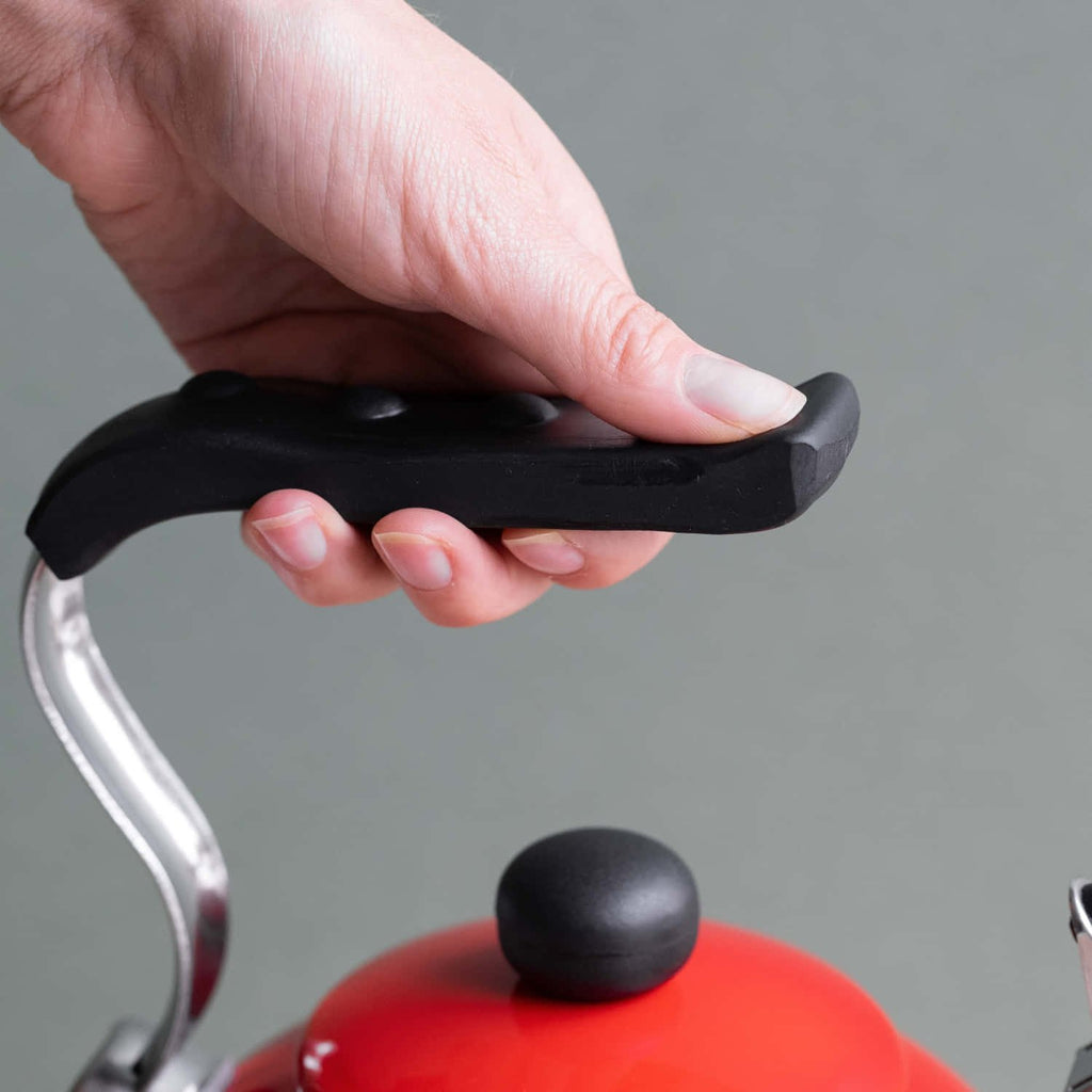 4. Hand holding black heat-resistant handle of red La Cafetière kettle