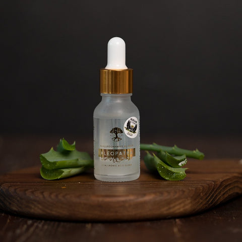 1. HOIA homespa Hyaluronic Acid Elixir Kleopatra bottle on wooden surface with aloe leaves, lifestyle setting
